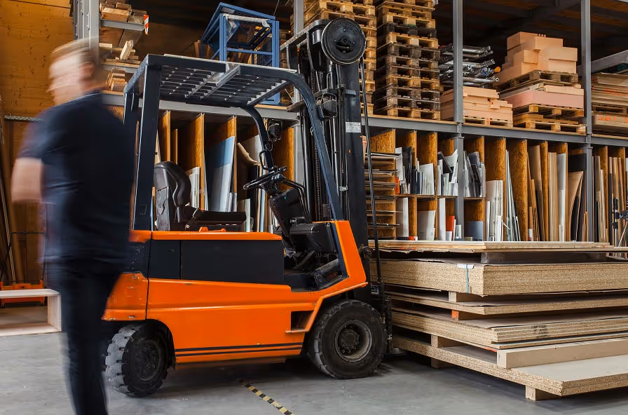 A worker moving materials with a forklift in a construction warehouse